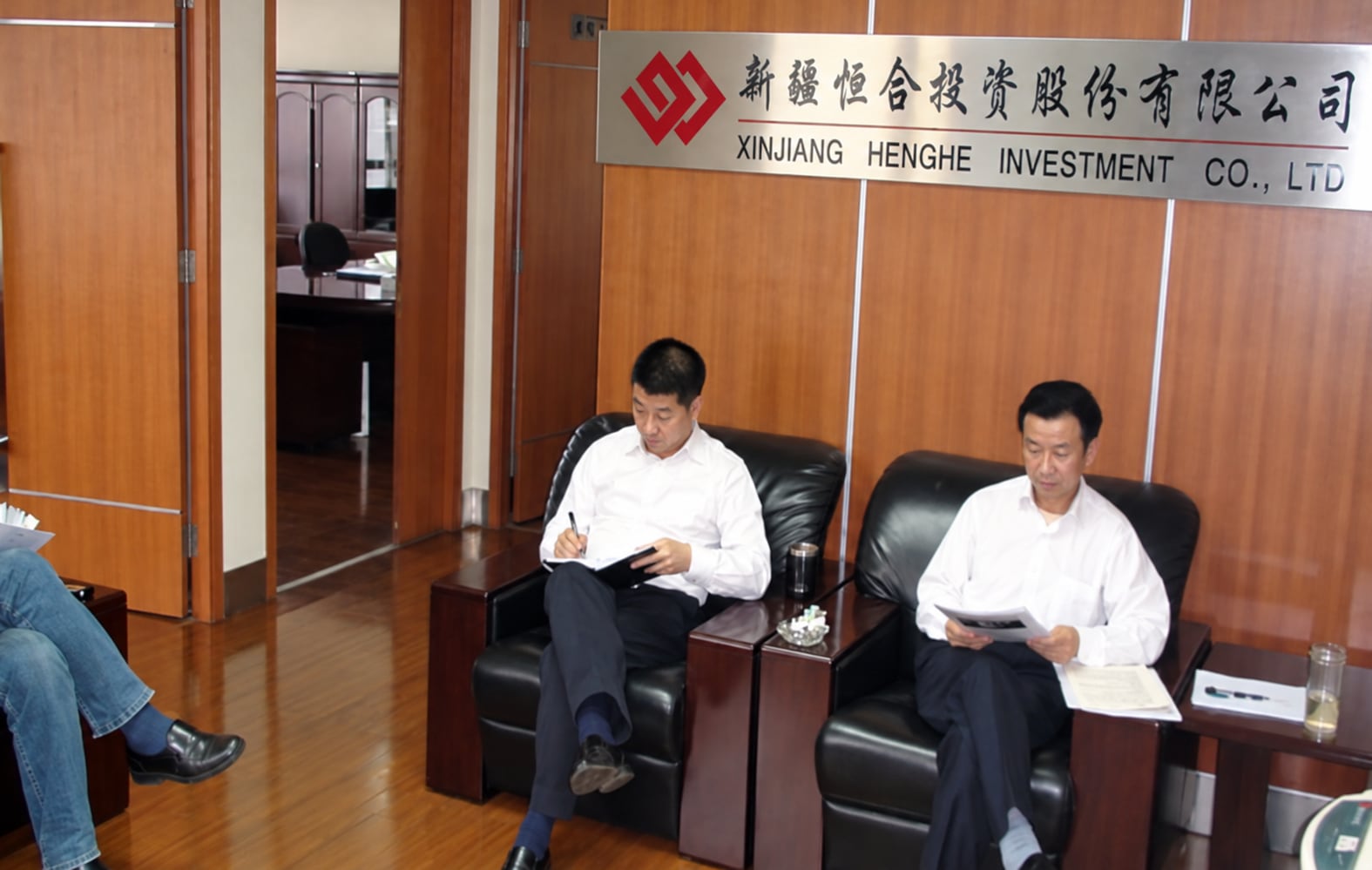 新疆恒合投资股份有限公司接待室，木质墙面上设有公司名称与标识