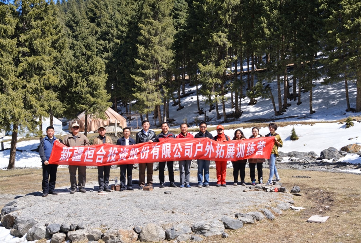 新疆恒合投资股份有限公司团队在雪地树林前手持公司横幅合影